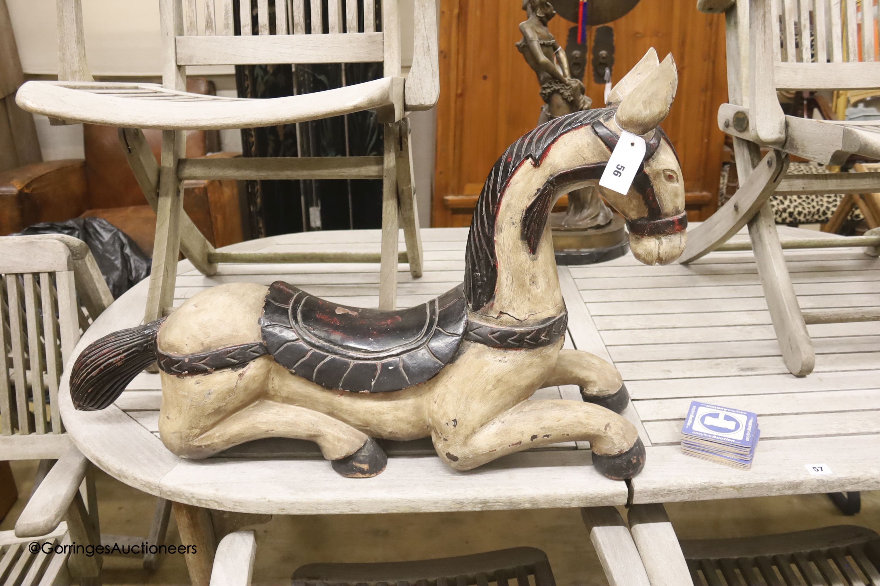 An Indonesian carved hardwood model of a recumbent horse, length 82cm, height 54cm